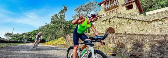 Triatleta pedalando diante do Pouso Paranapiacaba, cercado pela Mata Atlântica